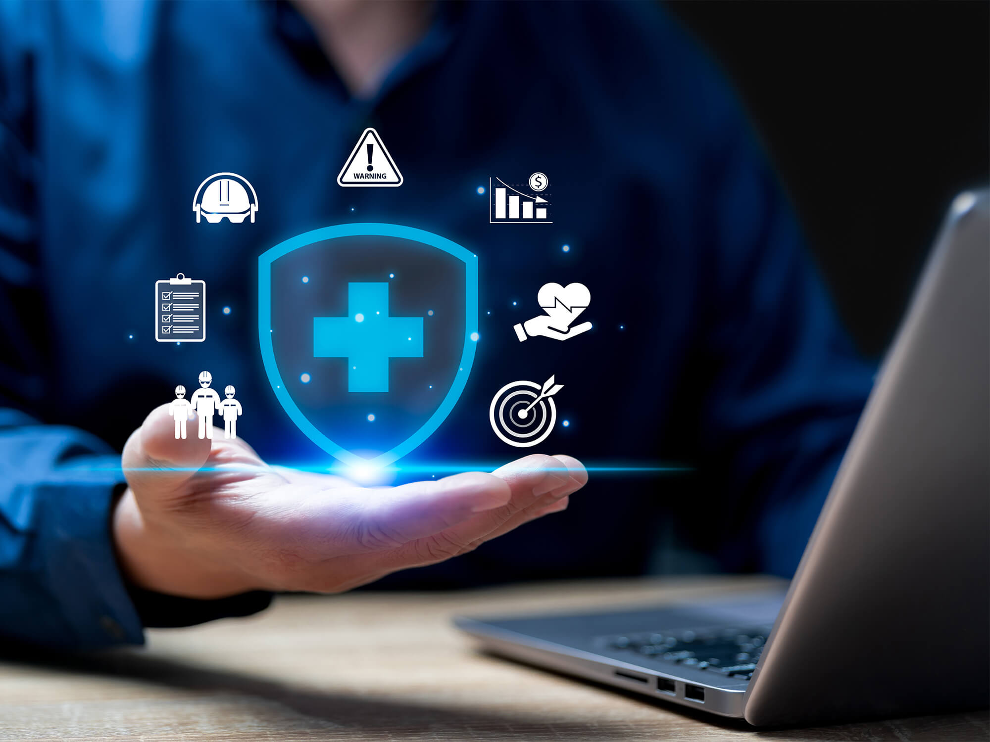 Nahaufnahme eines Versicherungsmaklers vor einem Laptop. Über seiner ausgestreckten Hand schwebt ein digitaler Schutzschild mit Symbolen für Sicherheit, Schutz und Zusammenarbeit – als Sinnbild für exklusive Deckungskonzepte, mit denen Gewerbekunden ihr Unternehmen gegen Risiken absichern.