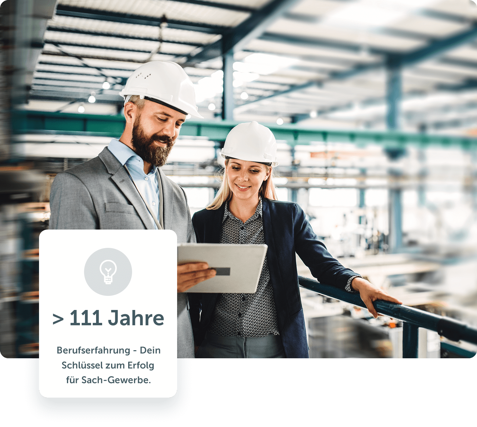 Ein Versicherungsmakler mit Schutzhelm zeigt in einer Fertigungshalle einer Frau etwas auf einem Tablet 